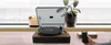 A turntable is placed on a wooden surface near a window, with a plant and a candle. Voir les images du produit
