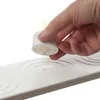 A hand is holding a white LED tea light over a white charging base with circular indentations. Produktbild-Vorschau