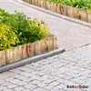 A garden border made of wooden planks is shown next to a paved walkway and a planter with green and yellow foliage. Produktbild-Vorschau
