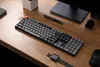A desk setup with a keyboard, monitor, pen, and watch. Produktbild-Vorschau