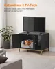 A cat is resting on a bed inside a black cabinet with a TV on top, in a living room setting. Produktbild-Vorschau
