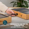 A hand is plugging a power cord into a modular grill unit, with text overlay indicating connectivity. Produktbild-Vorschau