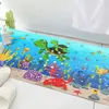 A colorful bath mat with an underwater theme, featuring turtles, fish, and a crab, placed next to a bathtub. Produktbild-Vorschau