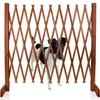 A dog is standing behind a wooden expandable gate. Produktbild-Vorschau