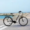 A silver electric bicycle is parked on a paved path next to a body of water. Produktbild-Vorschau