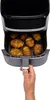 A hand is pulling out the basket of an air fryer filled with Hasselback potatoes. Produktbild-Vorschau