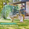A boy and a dog playing in a backyard with a security camera in the background. Produktbild-Vorschau