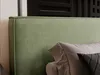 A close-up view of a green upholstered headboard with pillows. Produktbild-Vorschau