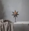 A star-shaped lamp sits on a table next to a draped cloth and dried branches. Podgląd zdjęcia produktu