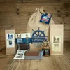 A collection of gourmet food products arranged on a wooden surface, with a large burlap sack in the background. Produktbild-Vorschau