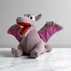 A plush toy of a dragon-like creature sitting on a marble surface against a plain background. Produktbild-Vorschau