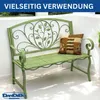A green metal garden bench with decorative scrollwork and leaf motifs, placed on an outdoor patio with dappled sunlight. Podgląd zdjęcia produktu