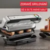 A close-up of an electric grill with meat cooking on it, placed on a kitchen counter. Voir les images du produit