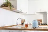 A clean, modern kitchen counter with a blue electric kettle, a cup of tea, and sink area. Náhled obrázku produktu