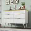A white dresser with gold accents and decorative items on top, set against a light green wall. Podgląd zdjęcia produktu