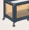 A close-up view of the bottom corner of a blue and gray baby travel cot with orange mesh sides. Anteprima dell’immagine prodotto