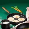 A frying pan with pancakes cooking, a pot of milk, and carrots on a green surface. Produktbild-Vorschau