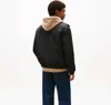 A man is shown from the back wearing a black jacket over a beige hoodie and blue jeans. Voir les images du produit