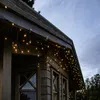 Icicle lights are strung along the eaves of a wooden cabin. Podgląd zdjęcia produktu