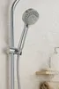 A close-up of a chrome hand shower head with water spraying from it, mounted on a shower rail. A bar of soap and a folded towel are visible on a shelf in the background. Produktbild-Vorschau