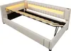 A beige upholstered bed frame with the mattress support mechanism lifted, revealing storage space underneath. The headboard has integrated LED lighting. Náhled obrázku produktu