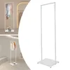A white metal clothing rack with clothes hanging on it, shown in a retail setting. Náhled obrázku produktu