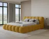 A bedroom with a large yellow upholstered bed, large windows with curtains, and a bedside table. Voir les images du produit
