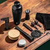 A collection of black barware tools laid out on a wooden surface. Voir les images du produit
