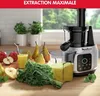 A juicer is shown on a kitchen counter with fruits and vegetables, suggesting fresh juice preparation. Náhled obrázku produktu