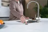 A person is using a sink with a modern faucet and a button on the countertop. Produktbild-Vorschau
