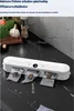 A white vacuum sealer machine is shown on a black marble countertop, with several vacuum-sealed bags containing brown items. In the background, there are vegetables, a garlic bulb, and a spice grinder. Produktbild-Vorschau