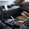 Two people using smartphones in a car, one charging a phone with a car charger. Produktbild-Vorschau