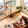 A living room scene with a TV stand, a sofa with a woman and child, and toys on the floor. Anteprima dell’immagine prodotto