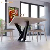 A dining table with a modern spider leg base and four chairs in a well-lit room with large windows. Náhled obrázku produktu