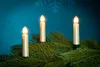 Three LED candles on a Christmas tree branch against a blue background with snowflakes. Produktbild-Vorschau