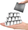 A hand holding a stack of stainless steel whiskey stones, with another hand holding a box above them. Produktbild-Vorschau