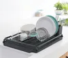 A dark gray dish drying rack filled with clean dishes, glasses, and cutlery, placed on a kitchen counter. Podgląd zdjęcia produktu