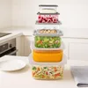 A stack of clear food storage containers filled with various foods, arranged on a kitchen counter. Náhled obrázku produktu