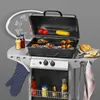 A Clatronic gas grill is set up with food cooking on it, alongside various condiments and a bread loaf. Produktbild-Vorschau