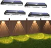Solar lights mounted on a fence illuminating the lawn below. Produktbild-Vorschau