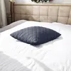 A dark gray quilted pillow on a white bed. Podgląd zdjęcia produktu