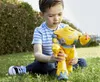 A young boy is playing with a yellow robot toy in a grassy outdoor setting. Produktbild-Vorschau