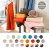 A collection of folded and rolled blankets in various colors, displayed on rustic wooden stools and a branch. Below, a grid of circular swatches shows many more color options for the blankets. Produktbild-Vorschau
