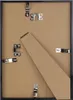 The back of a black picture frame with a cardboard insert and various metal clips and fasteners. Produktbild-Vorschau