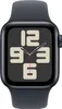 A close-up, front-facing view of a smartwatch with a dark gray band and a dark gray watch face displaying a clock with large beige numbers and red and black hands. Voir les images du produit