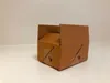 A brown cardboard box with its flaps open, sitting on a white surface against a light gray wall. Produktbild-Vorschau