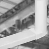 A close-up view of a white plastic ventilation duct elbow connector, with a blurred industrial background. Produktbild-Vorschau