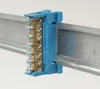 A close-up of a blue terminal block mounted on a metal rail. Produktbild-Vorschau