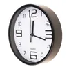 A close-up, angled view of a black and white analog wall clock against a white background. Voir les images du produit