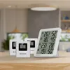 Three white digital thermo-hygrometers are displayed on a wooden table in a well-lit room. Produktbild-Vorschau